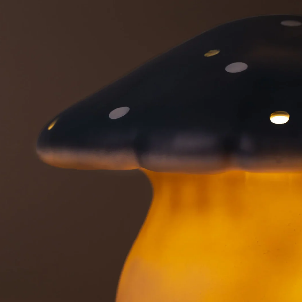 Mushroom-shaped lamp with a dark cap and glowing orange stem on a brown background