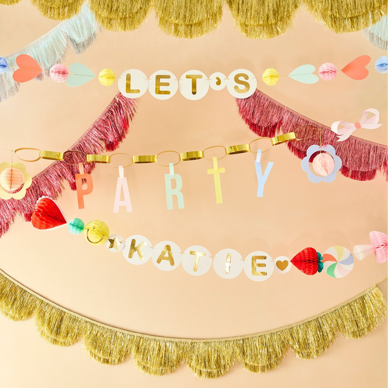 Colorful 'Let's Party' banner with tassels on a beige background
