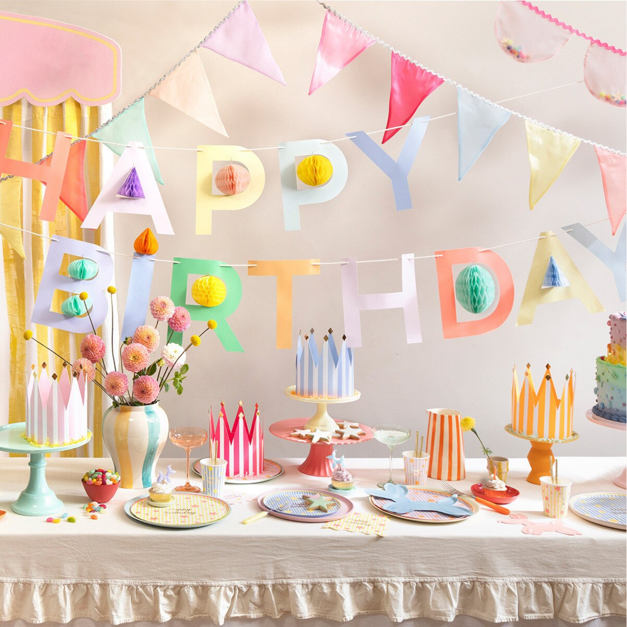 Colorful birthday party setup with 'Happy Birthday' banner, tableware, and decorations.