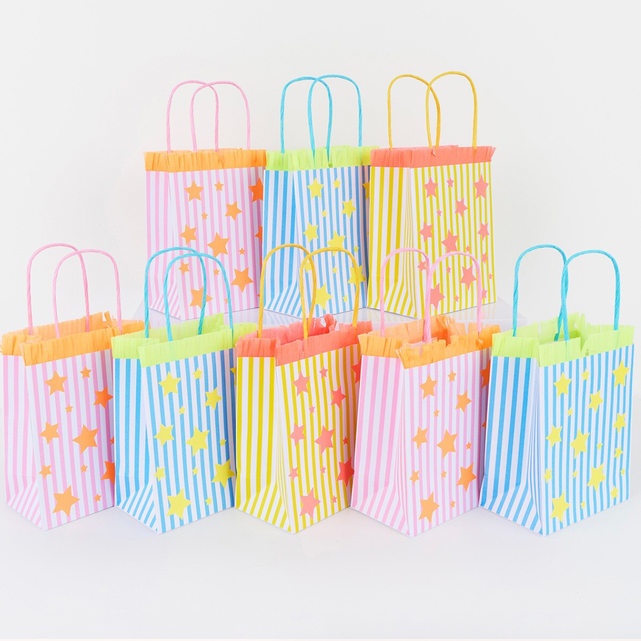 Colorful paper gift bags with star patterns on a white background