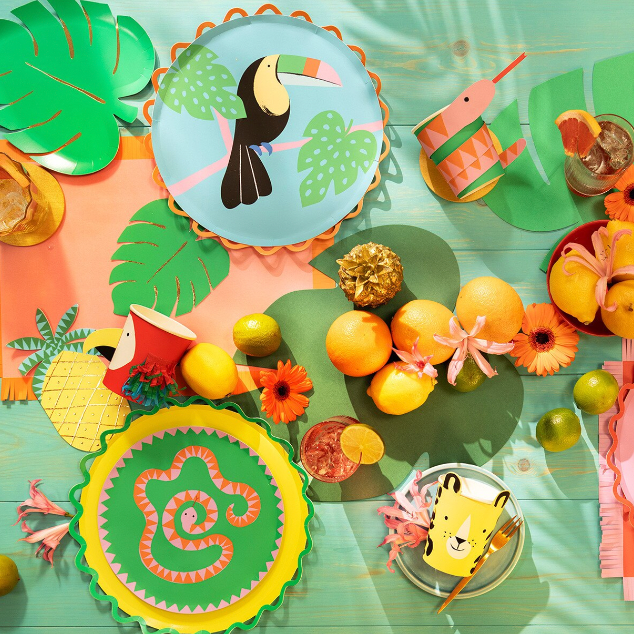 Colorful children's tableware set with animal-themed plates and cups on a green background.