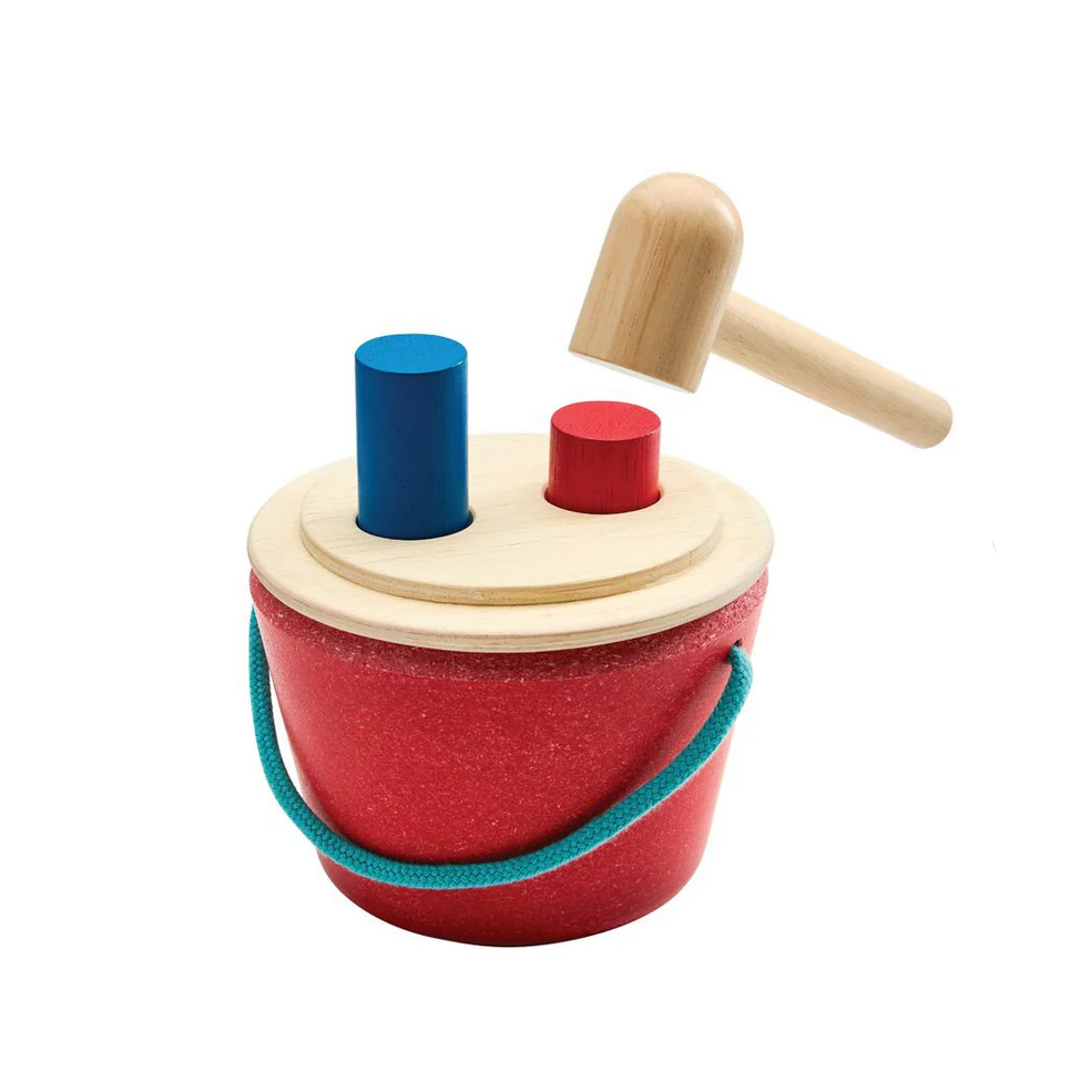 Wooden toy with a red bucket, blue cylinder, and wooden mallet on a white background
