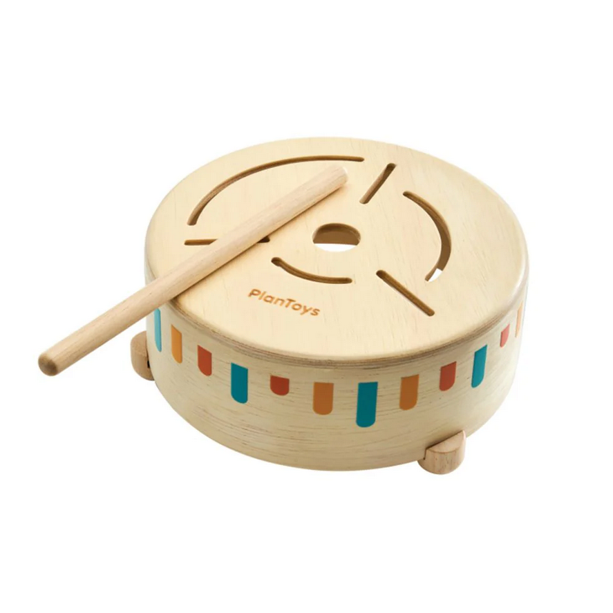 Wooden toy drum with colorful stripes and a wooden stick on a white background