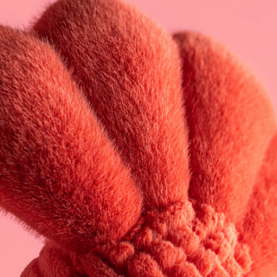 Close-up of a textured pink outfit labeled 'Larry Lobster Sailor Outfit' on a pink background