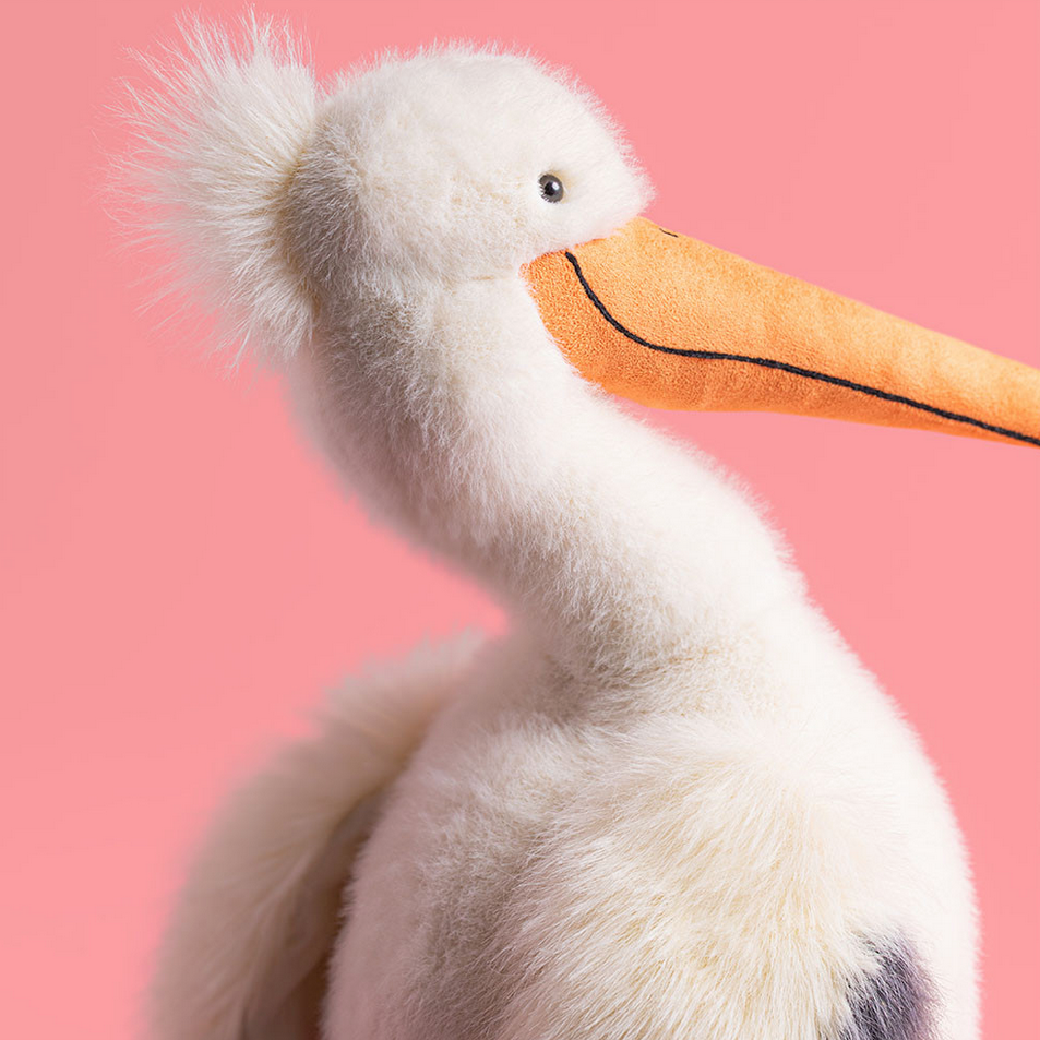 Stuffed pelican toy against a pink background