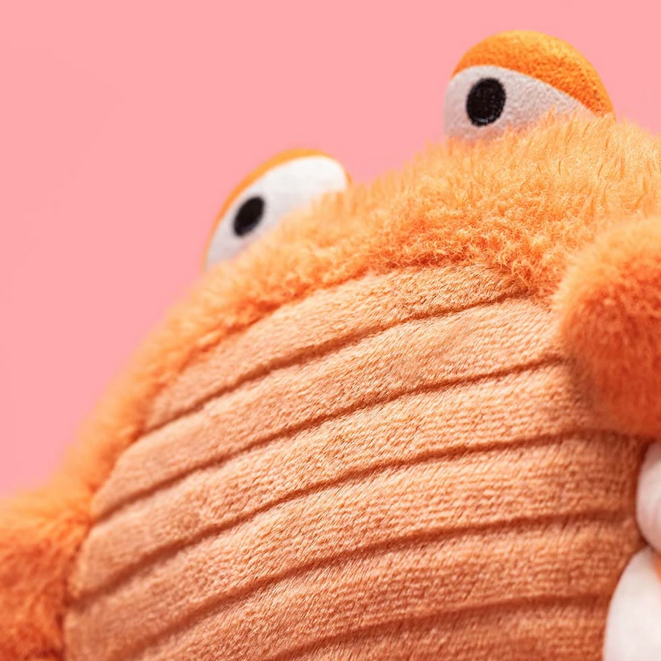 Close-up of a plush Pinchsnap Crab toy against a pink background