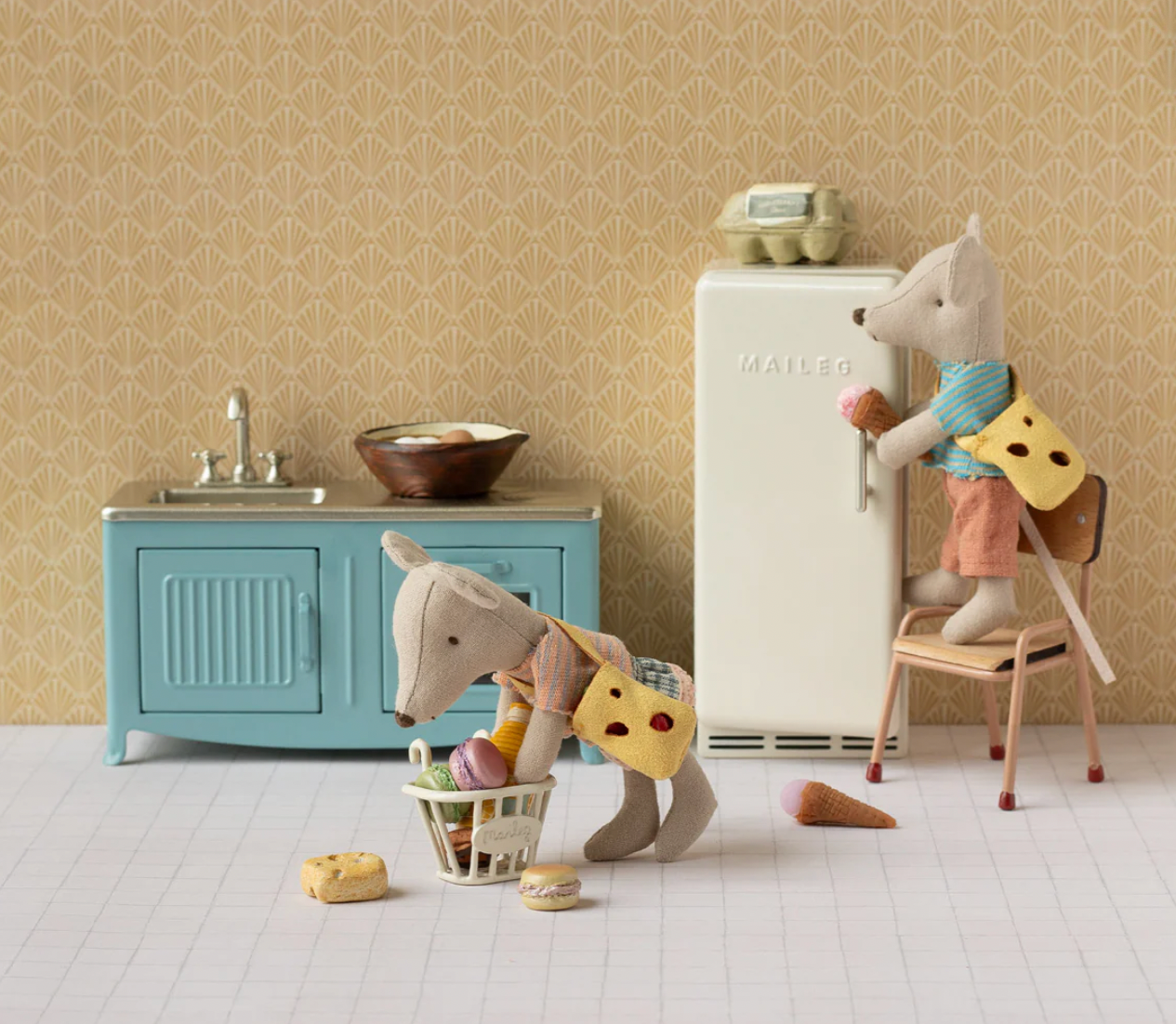 Toy mice in a kitchen setting with a refrigerator and sink.