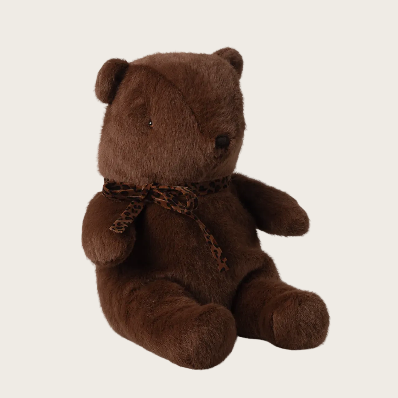 Brown teddy bear with a bow tie on a light beige background