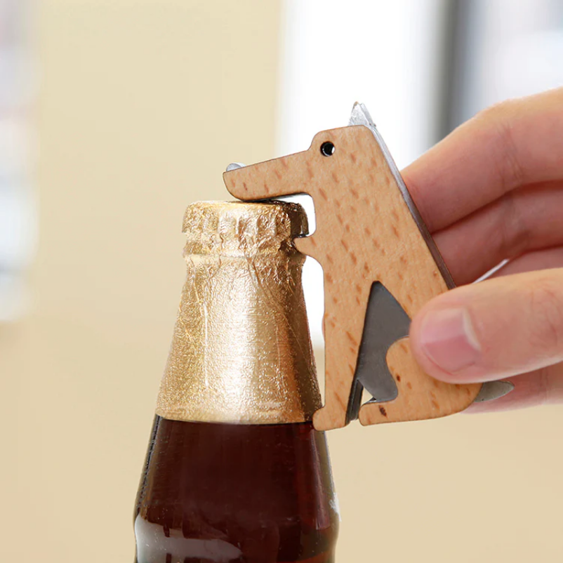 Dog-shaped bottle opener being used on a bottle with a blurred background