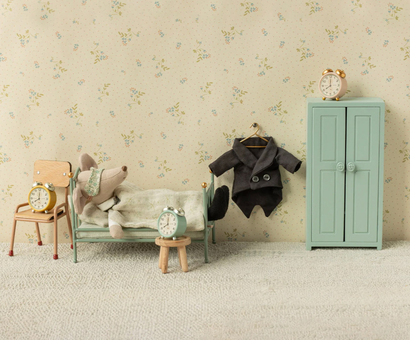 Children's room with mint green furniture, toys, and a clock against a floral wallpaper.