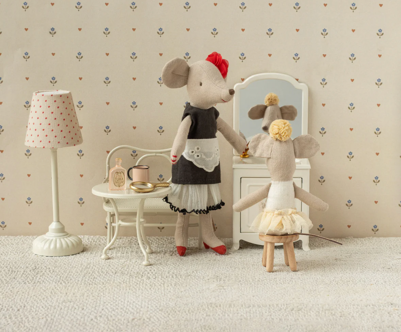 Two toy mice in a room with a lamp and mirror on a patterned wall.