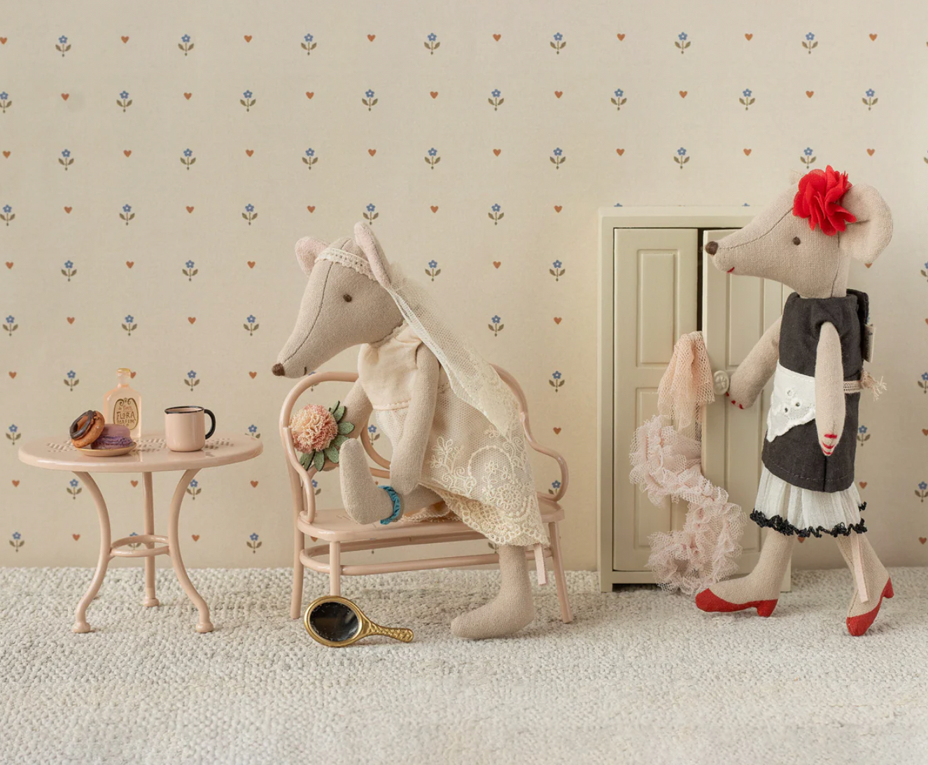 Two plush mouse toys in a decorative room with wallpaper and furniture.