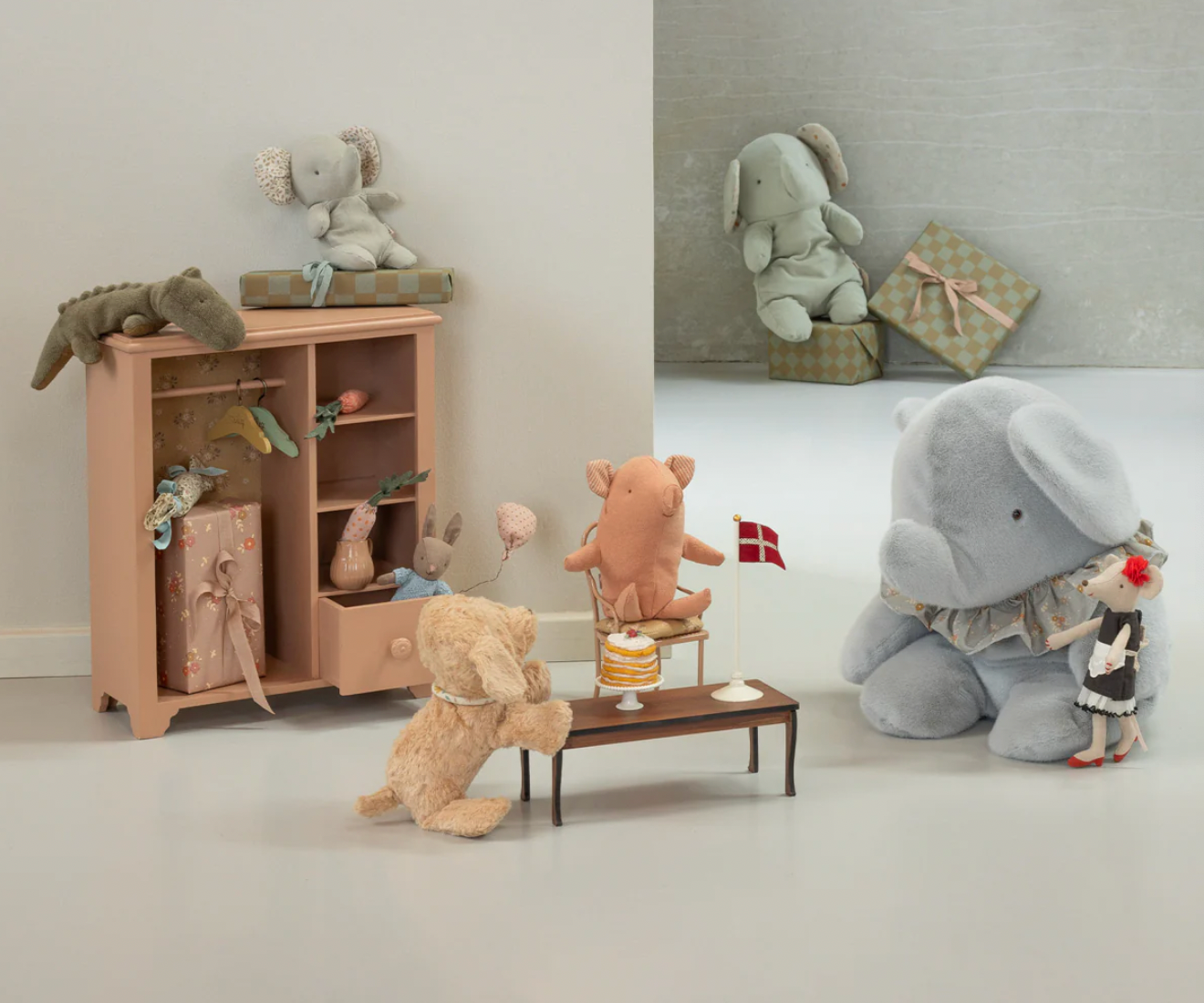 Toy elephant and bear with a cake on a shelf in a room setting.