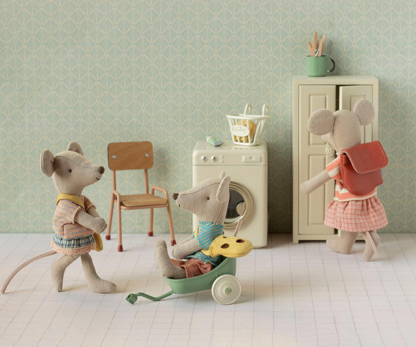 Toy mice in a room with a chair, washing machine, and dresser.