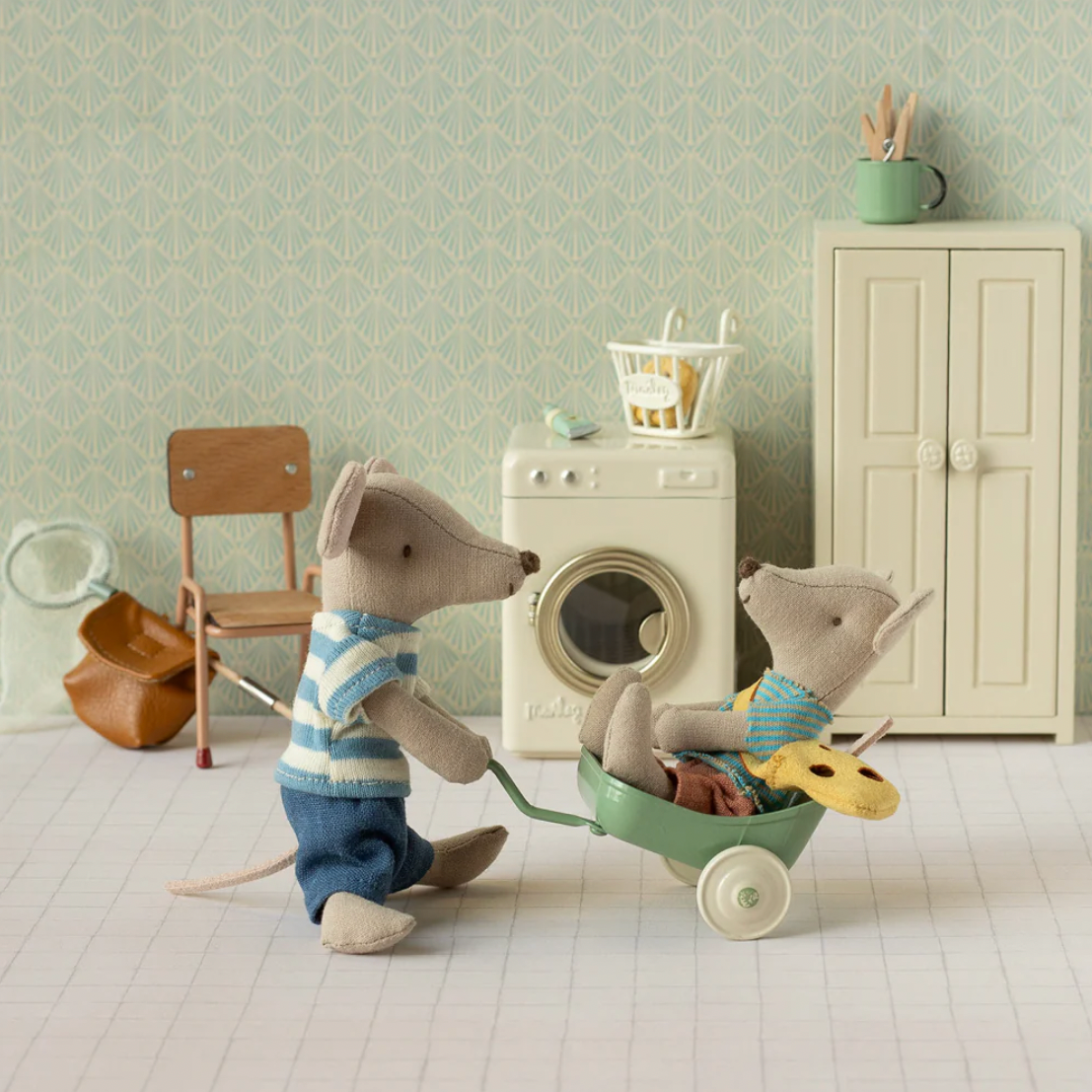 Two toy mice with a wheelbarrow in a room setting 