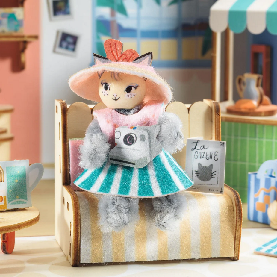 Toy figure of a cat in a dress with a hat in a miniature room setting
