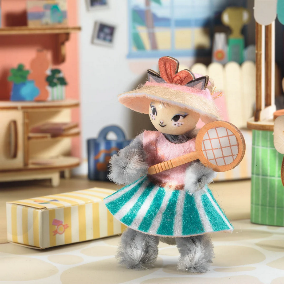 Toy figure in a dress with a hat and tennis racket in a colorful room setting
