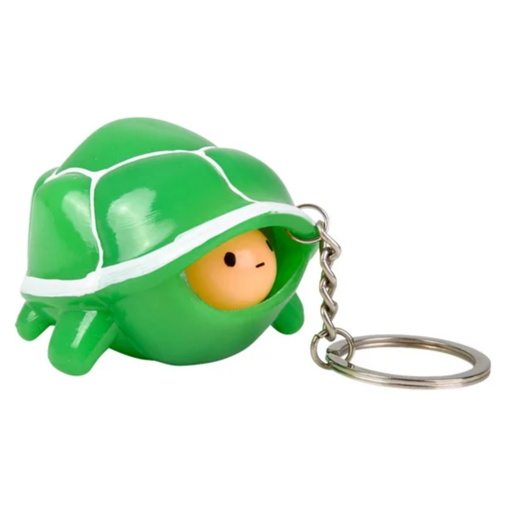 Green turtle-shaped keychain with a small face on a white background