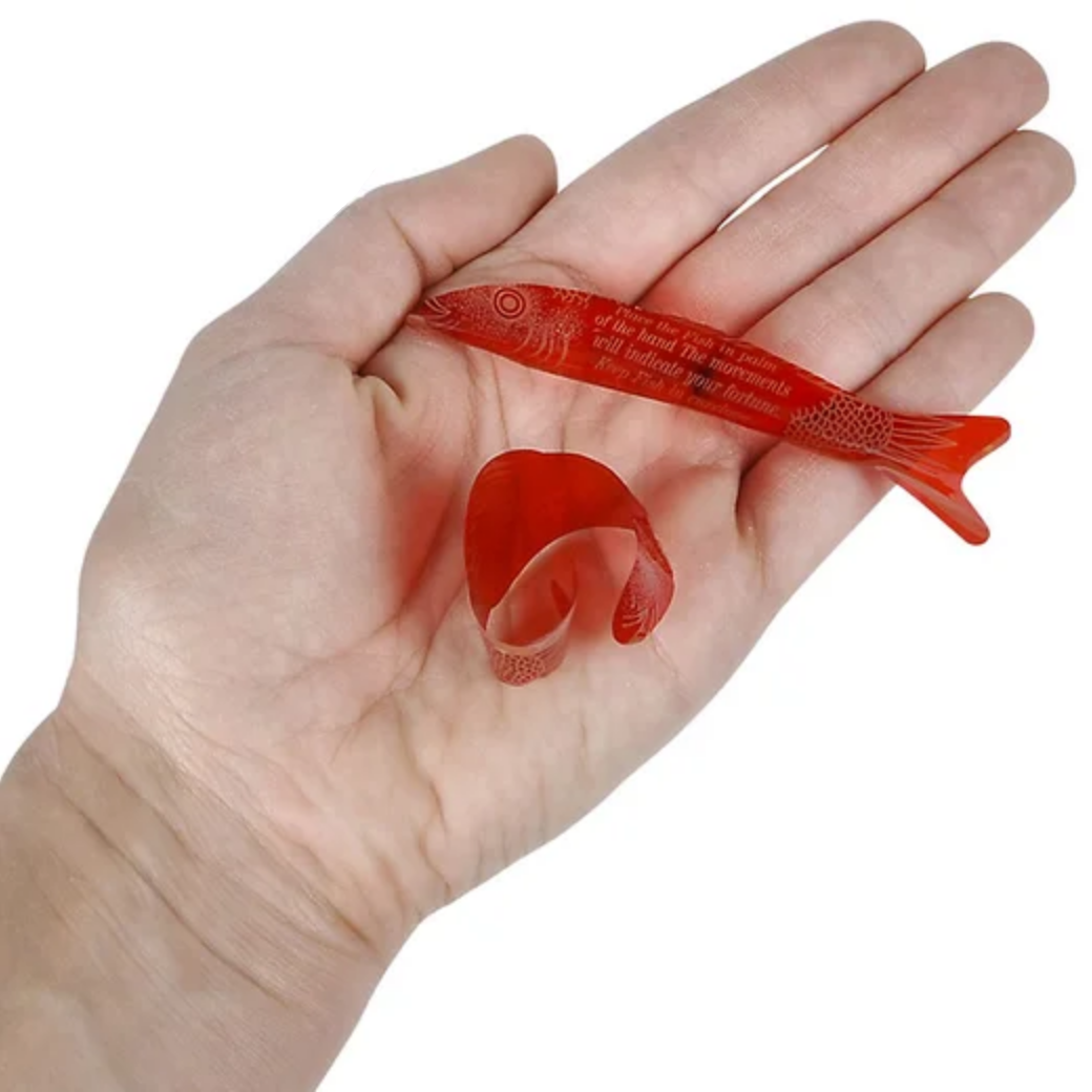 Hand holding a red fish-shaped object with text on a white background
