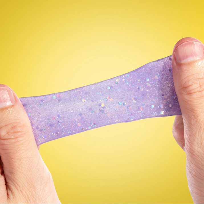 Hand holding a strip of glittery purple putty against a yellow background
