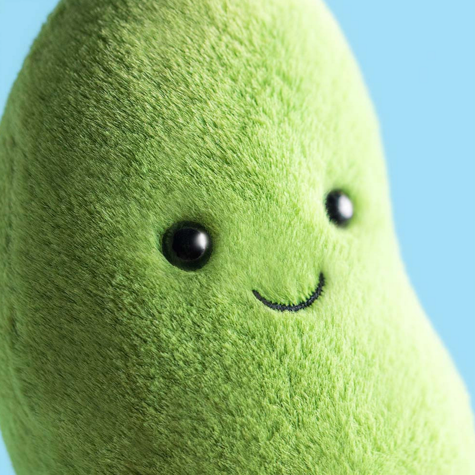 Plush avocado toy with a smiley face on a blue background