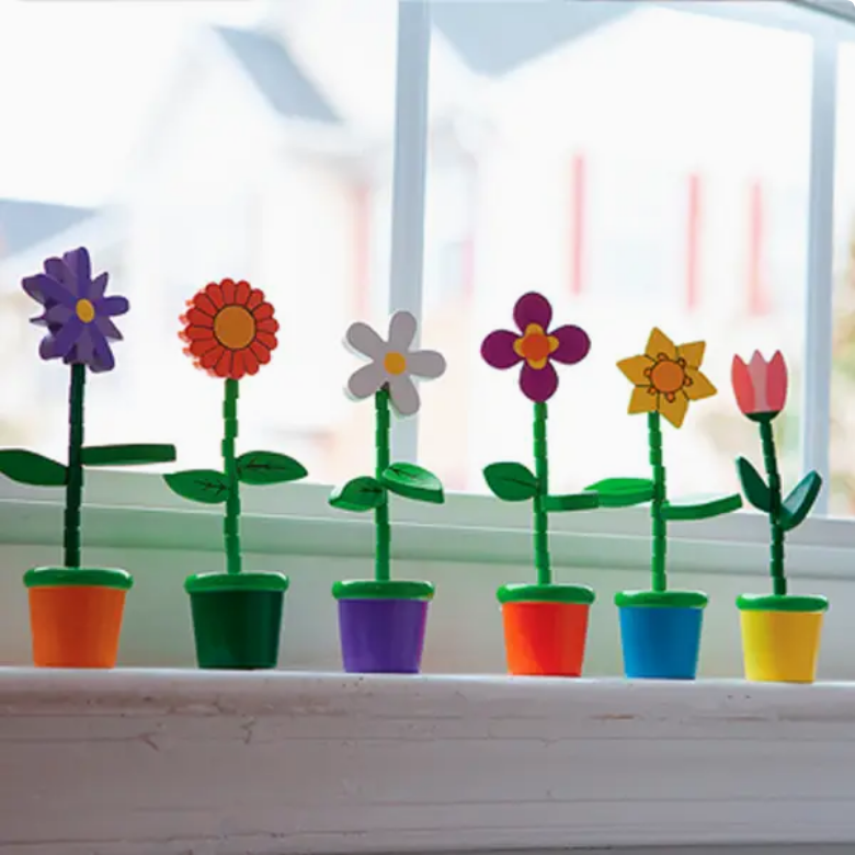 Colorful paper flowers in pots on a windowsill with a blurred outdoor background