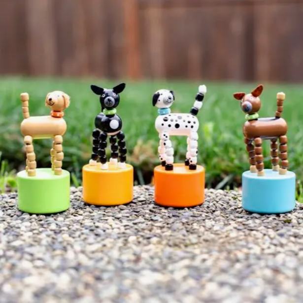 Four colorful dog figurines on stands outdoors.