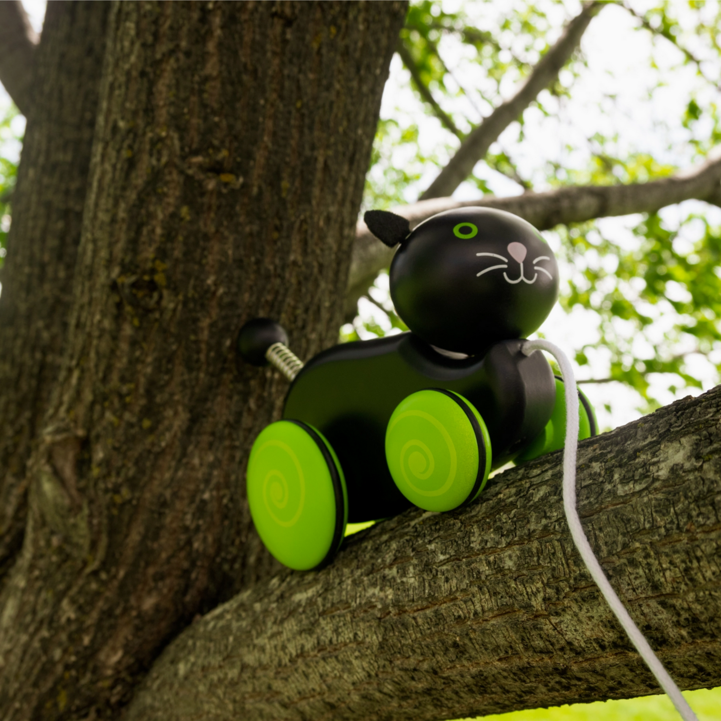 Toy resembling a cat with green wheels on a tree branch