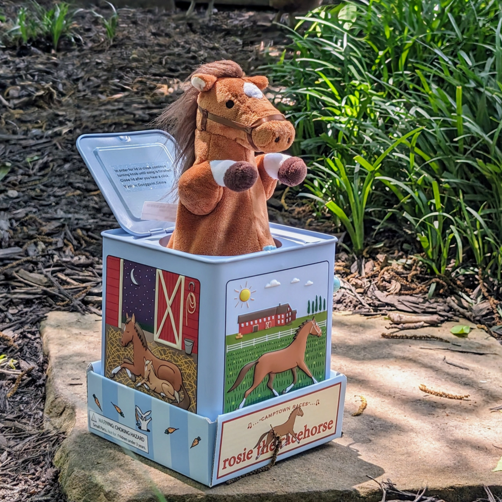 Jack-in-the-box toy horse with open lid in a garden setting