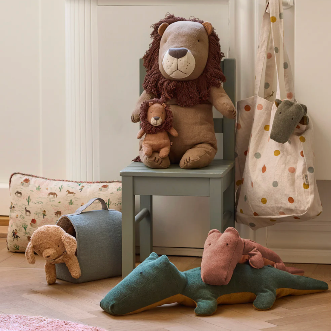 Children's room with stuffed animals on a chair and floor, computer screen displaying product details.