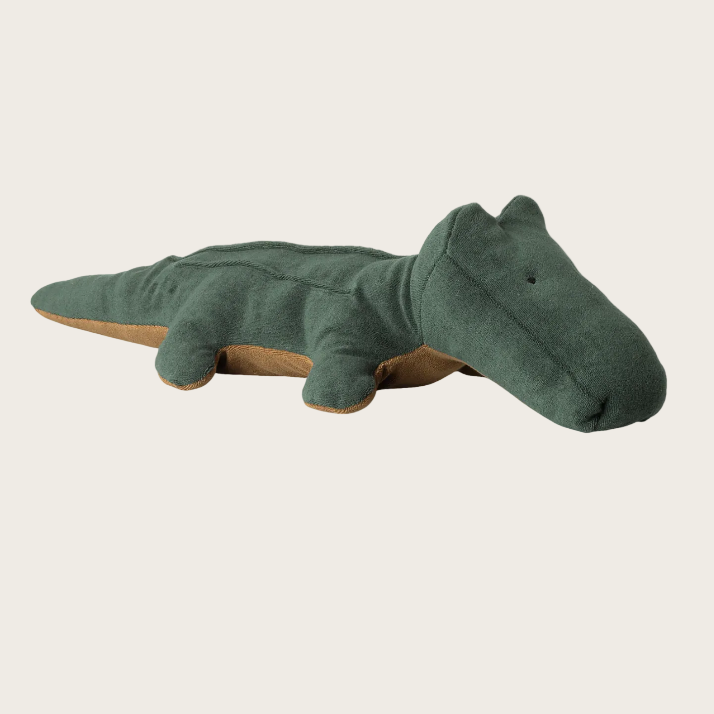 Green plush toy alligator on a light beige background