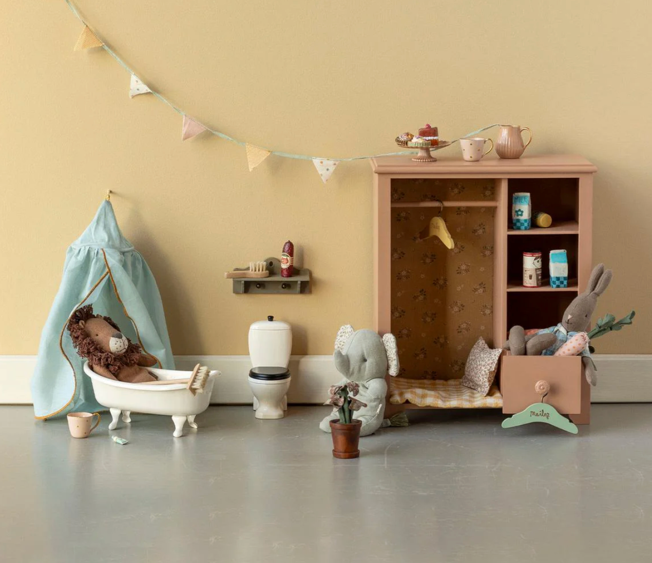 Children's playroom with toys and furniture against a beige wall.