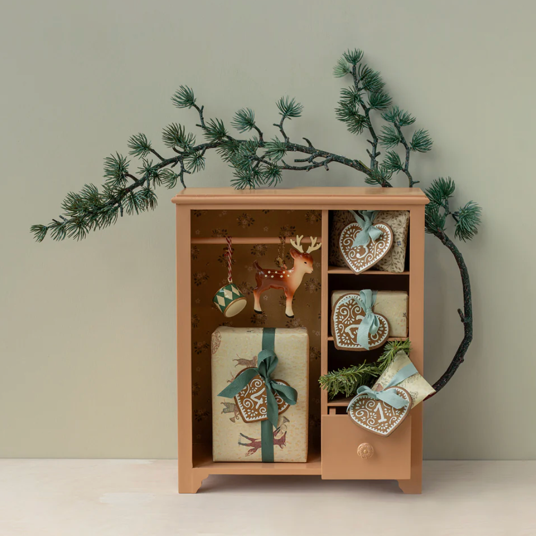Wooden cabinet with decorative items and a branch on a light gray background