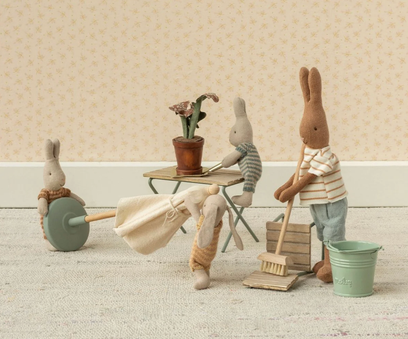 Miniature scene with toy bunnies in a room setting, one holding a broom and another with a bucket.