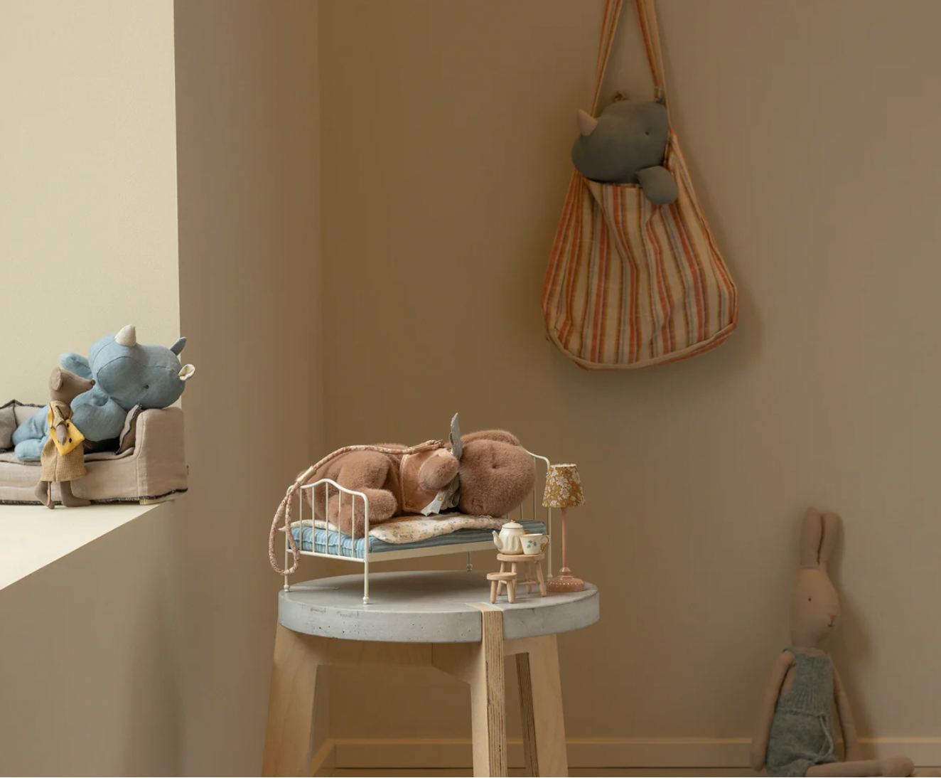Children's room with toys and a striped bag on a beige wall.