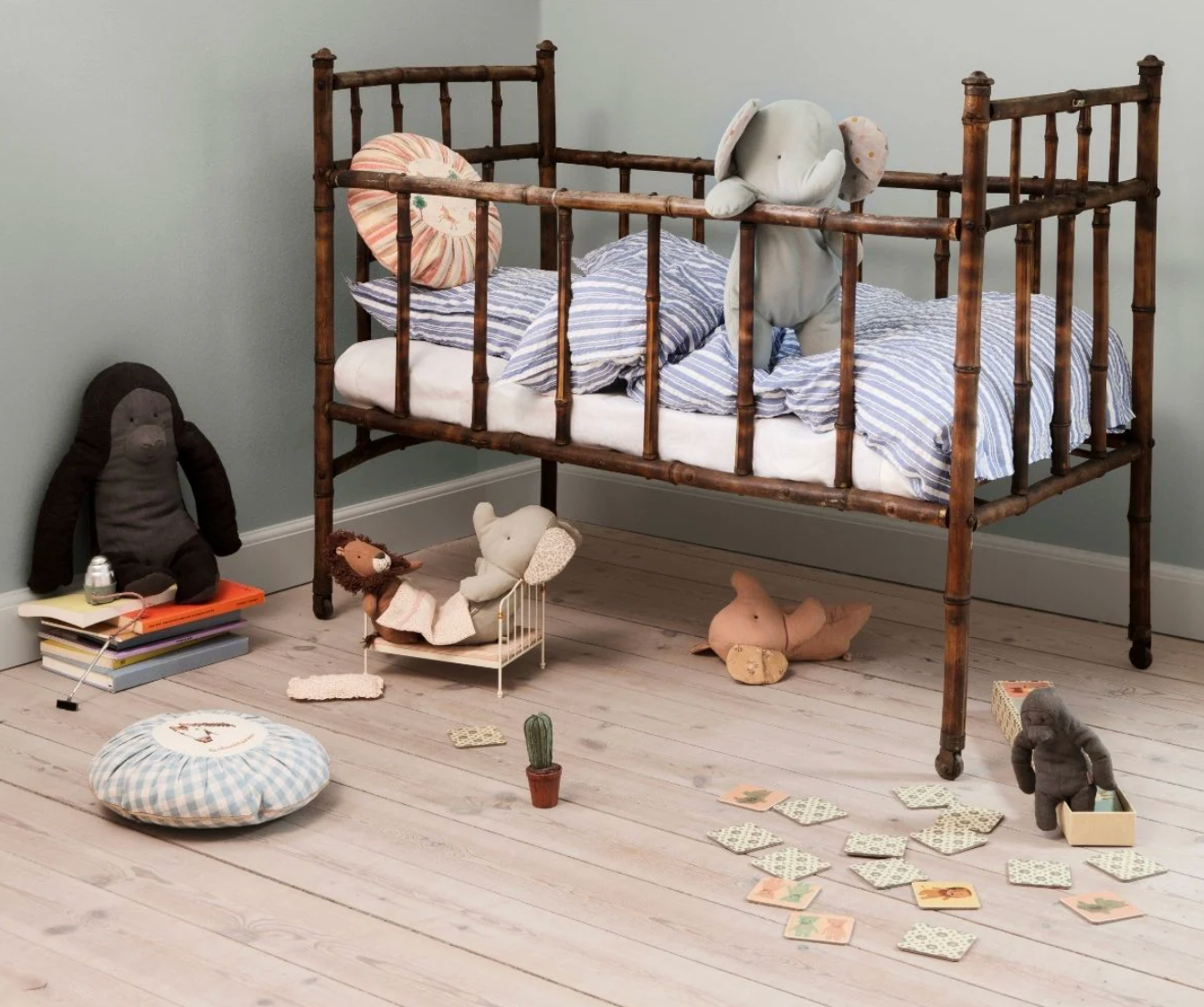 Children's bedroom with a wooden crib, toys, and books on a wooden floor.