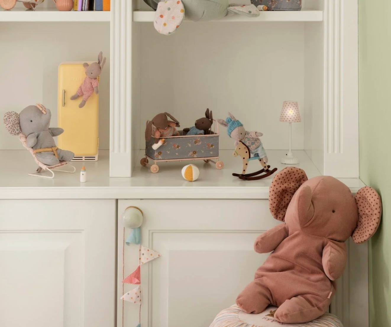 Children's toys including a teddy bear, rocking horse, and dolls in a display cabinet.