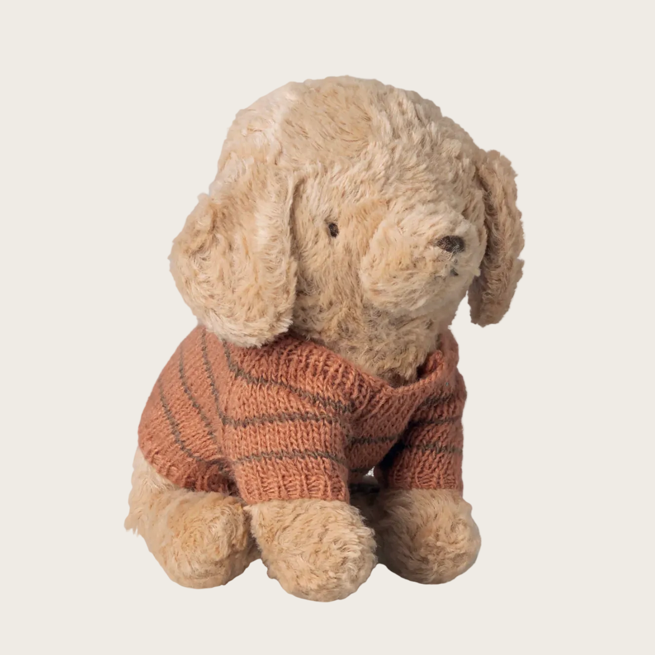 Stuffed dog toy wearing a knitted sweater on a white background