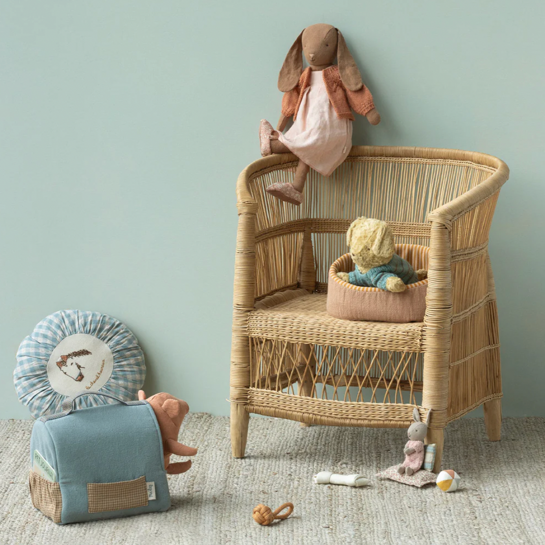 Wicker chair with toys in a room with a light blue wall
