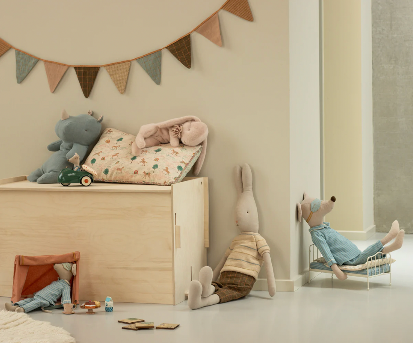 Children's room with toys and a wooden toy box against a beige wall.