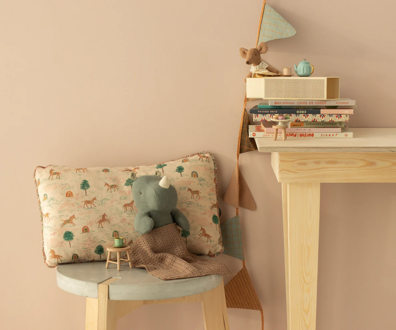 Children's room with a bench, cushion, and books against a beige wall.