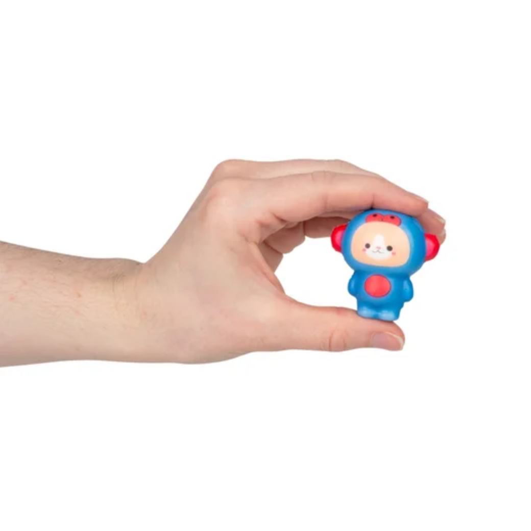 Hand holding a small blue toy figure with a red hat against a white background, 