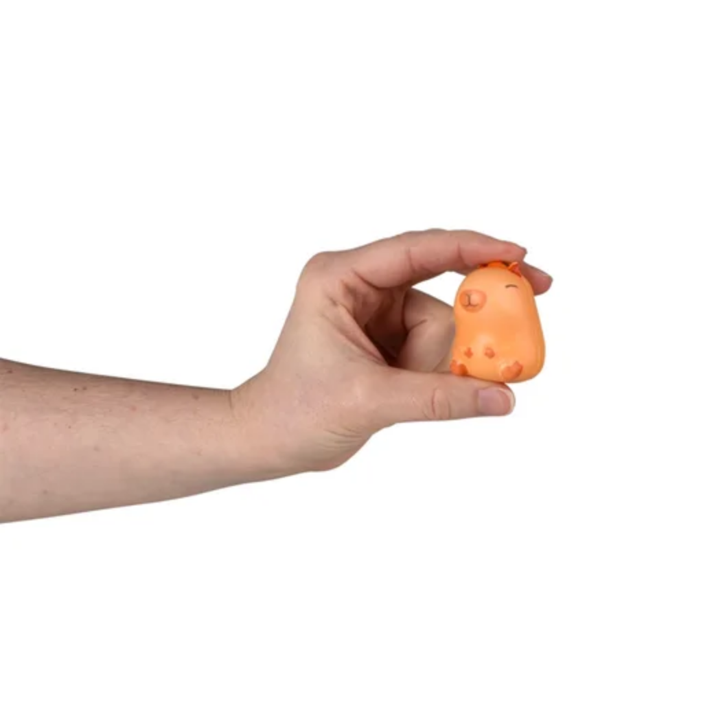 Hand holding a small orange novelty item with a face on a white background
