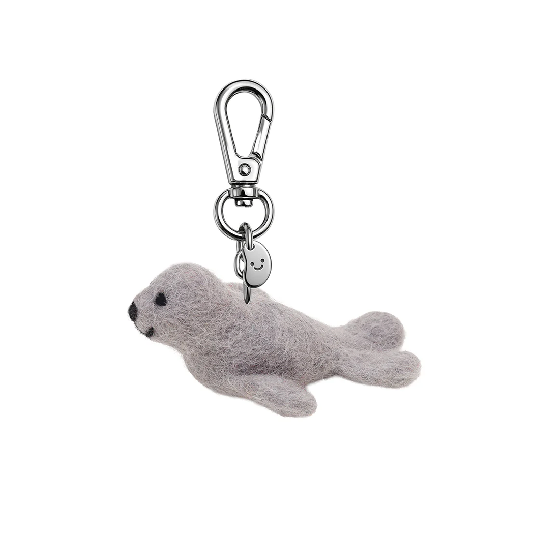 Gray seal-shaped keychain with a smiling face on a white background