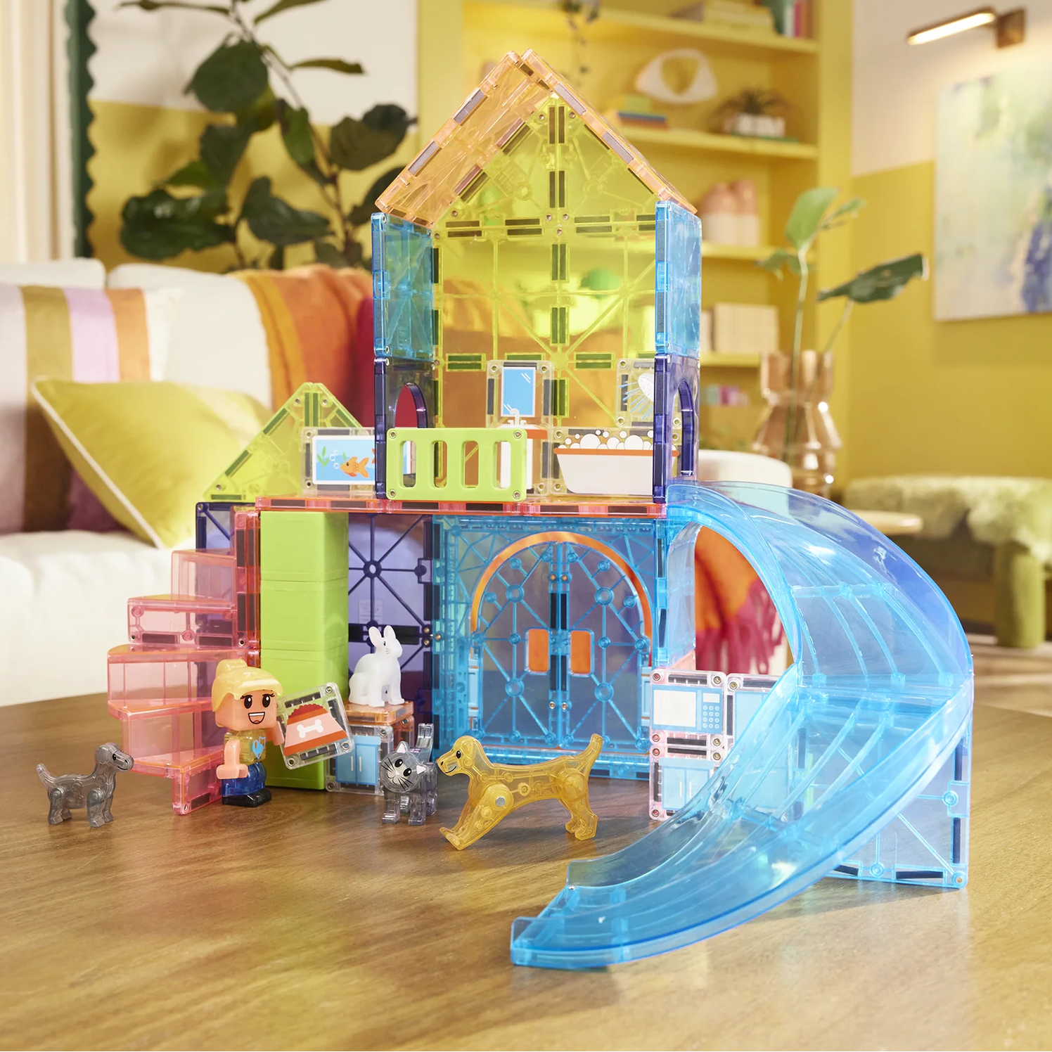 Colorful toy house with a slide on a wooden table in a bright room.
