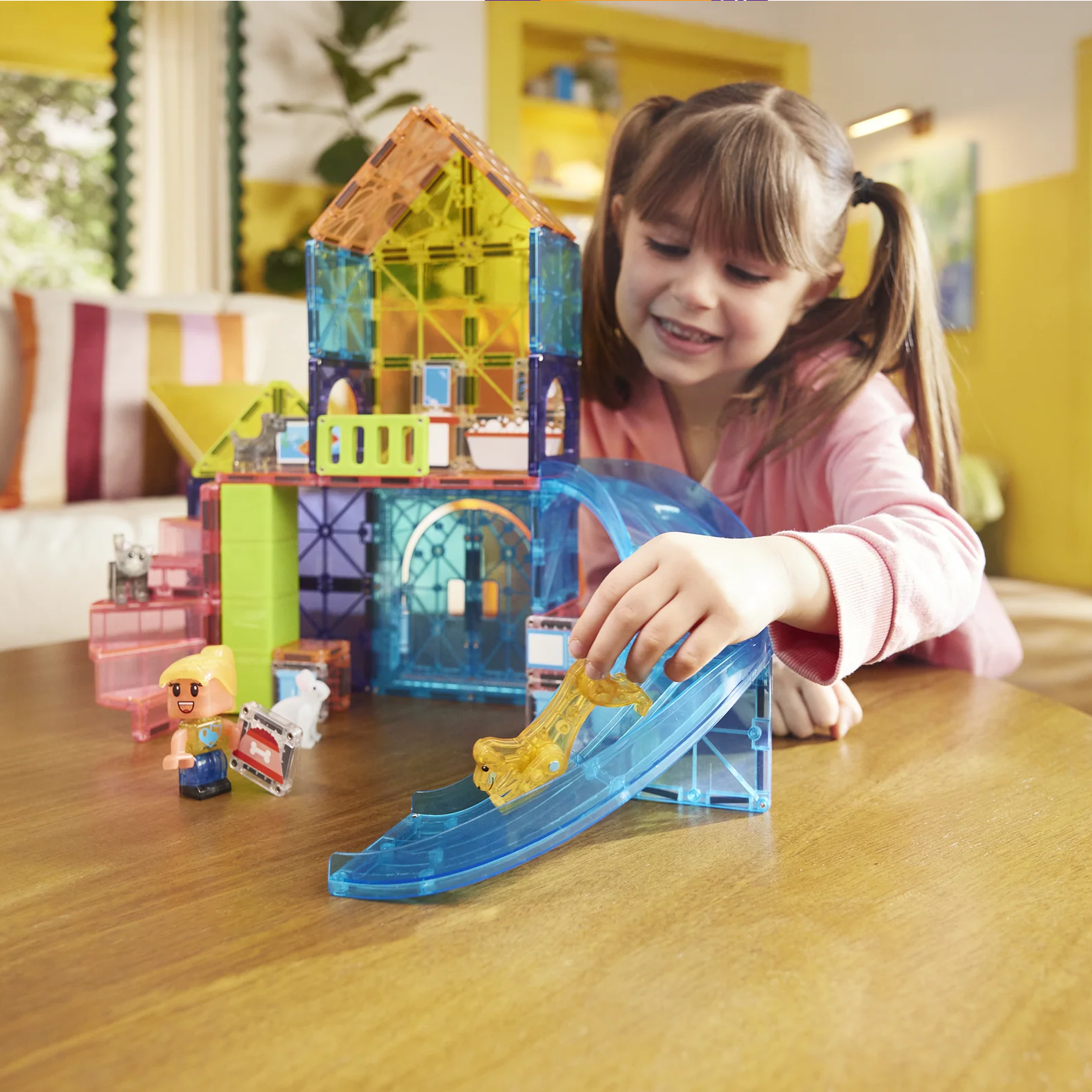 Child playing with colorful building blocks on a wooden table in a bright room.