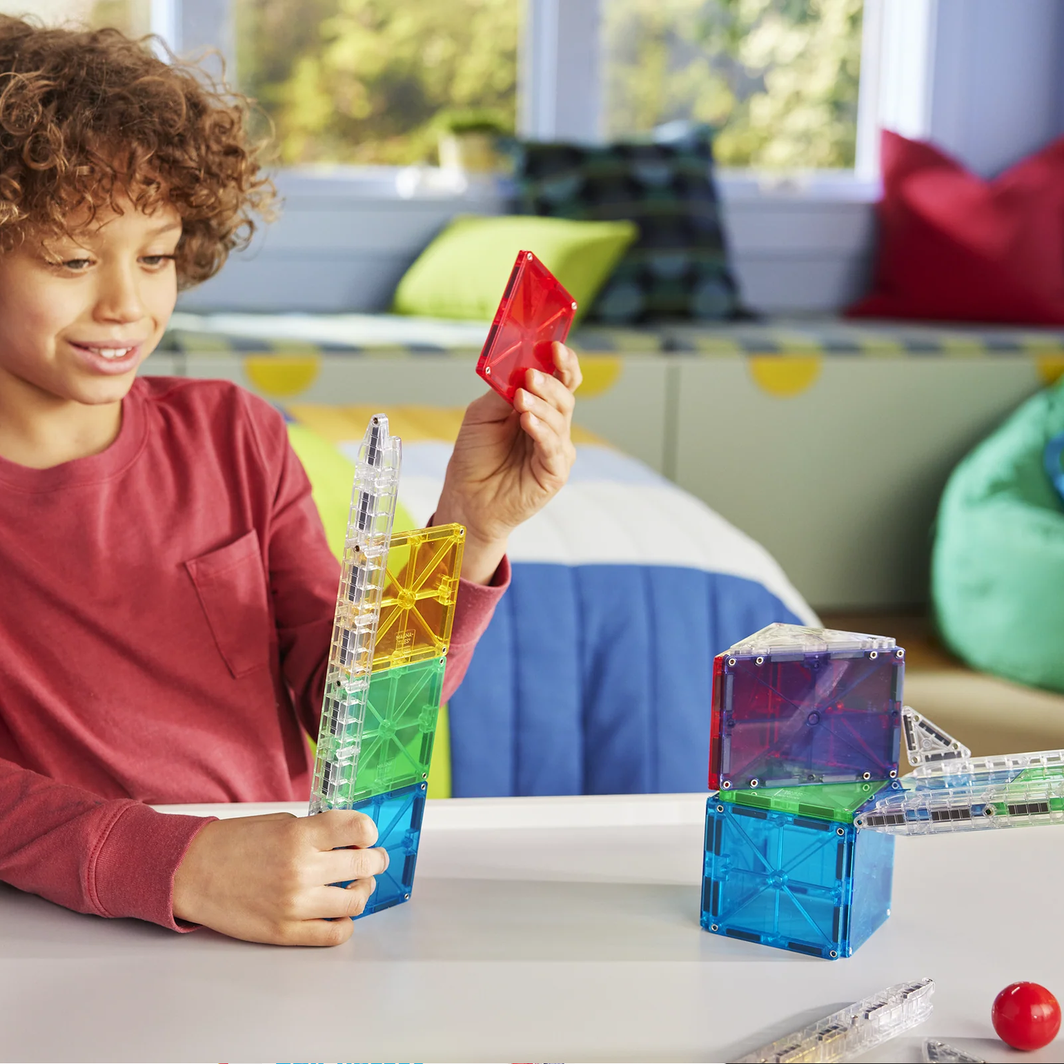 Child playing with colorful building blocks in a room with a couch and pillows.