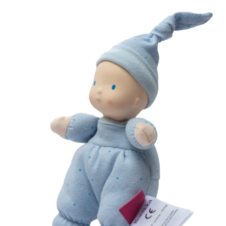 Baby doll in blue outfit with matching hat on a white background