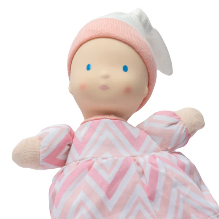 Baby doll with pink and white chevron patterned outfit on a white background