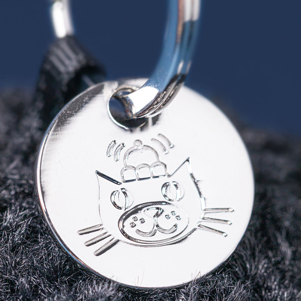 Silver cat-shaped pendant on a dark fabric background